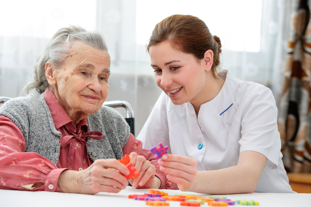 Compassionate caregiver assisting elderly person with dementia at home